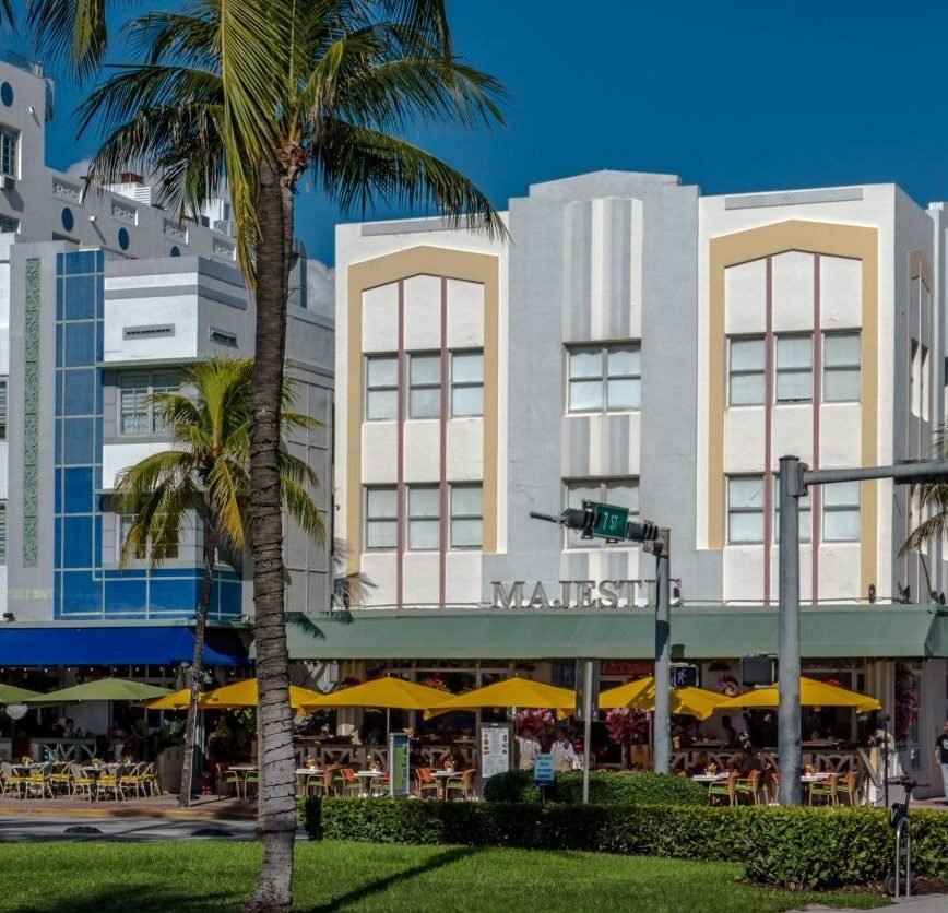 Fachada Art Déco del Majestic Hotel en Ocean Drive, Miami Beach, con balcones curvos y colores icónicos.