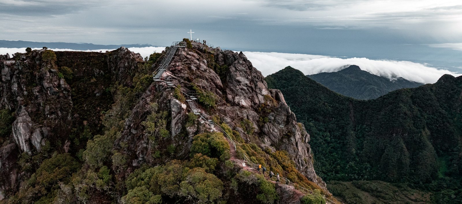 Vista aérea de la cima del Volcán Barú en Panamá con la cruz y senderistas entre las montañas.