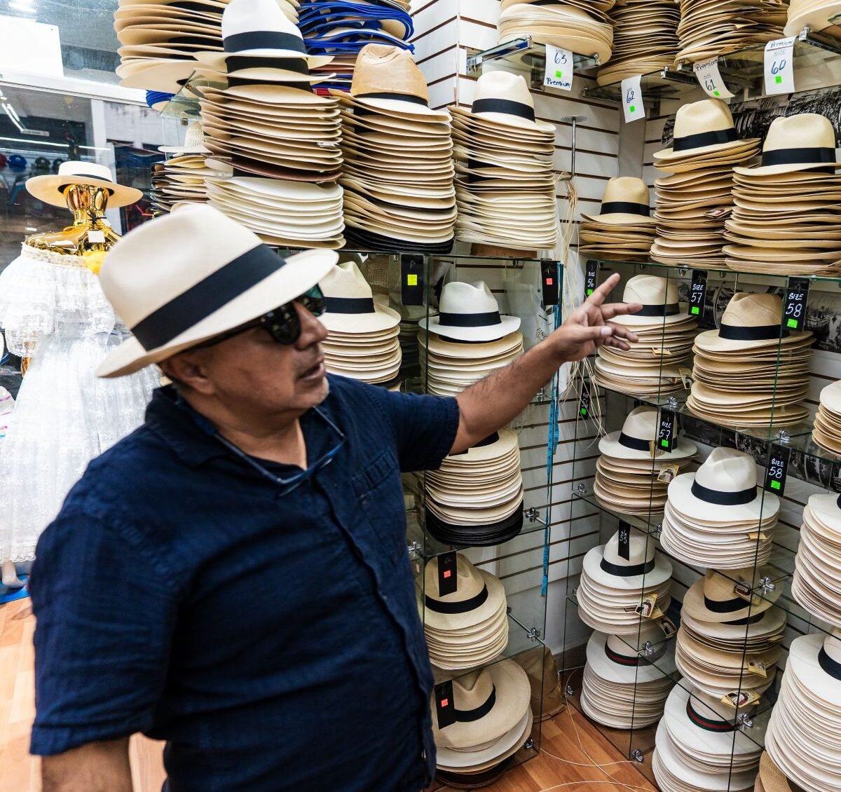 Man trying on a Panama hat in a traditional shop in Panama City, surrounded by handmade models.