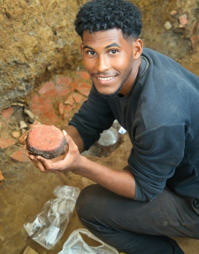 El estudiante Abdias Meneses. Está recogiendo una herramienta (martillo-gruñidor) de jade rojo. Tumba T3. El Caño. 2026