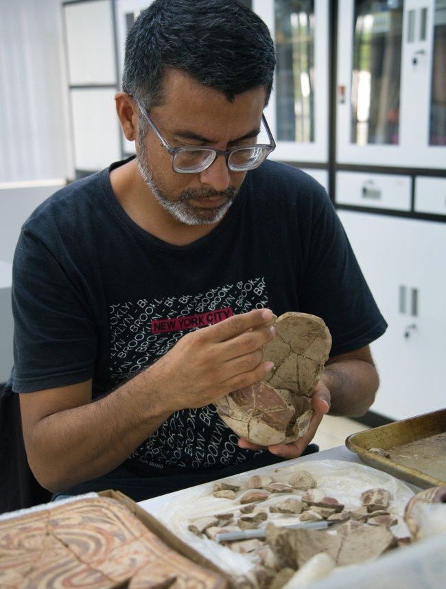 Elías Zaldívar, conservador de la Fundación El Caño y estudiante de último año de la Escuela de Antropología de la Universidad de Panamá pegando los fragmentos de una pieza de cerámica.